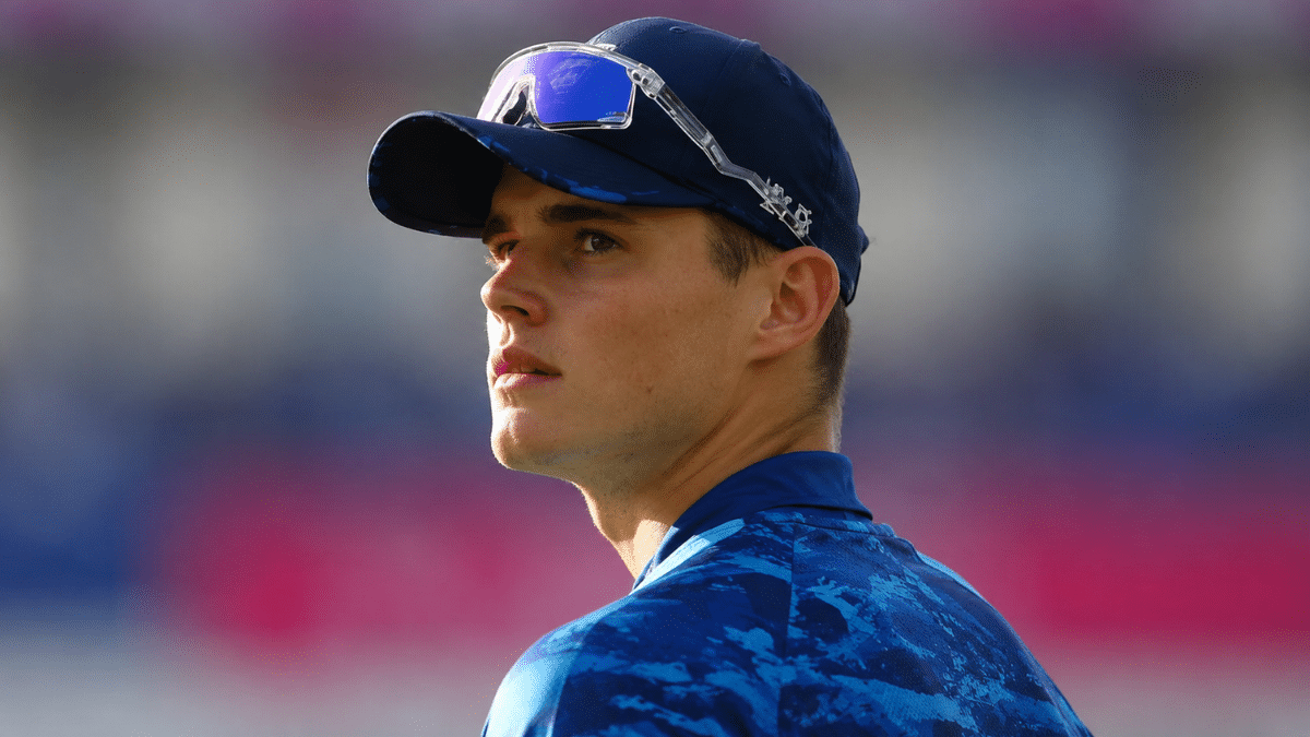 Jacob Bethell in blue sportswear looking sideways during a training session, with a blurred stadium background and natural lighting.