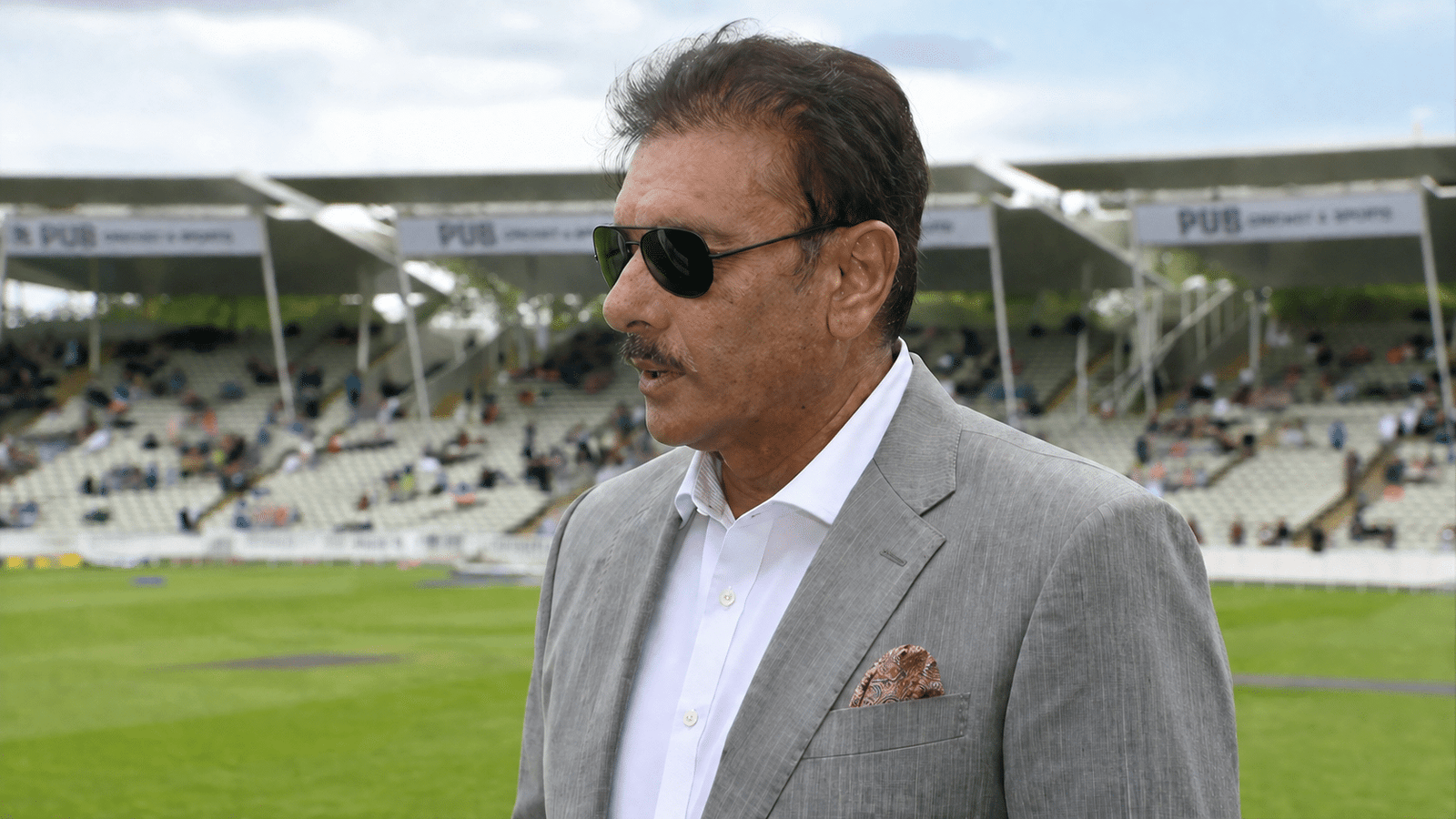 Former India cricket coach at a cricket stadium during match day with spectators in the background
