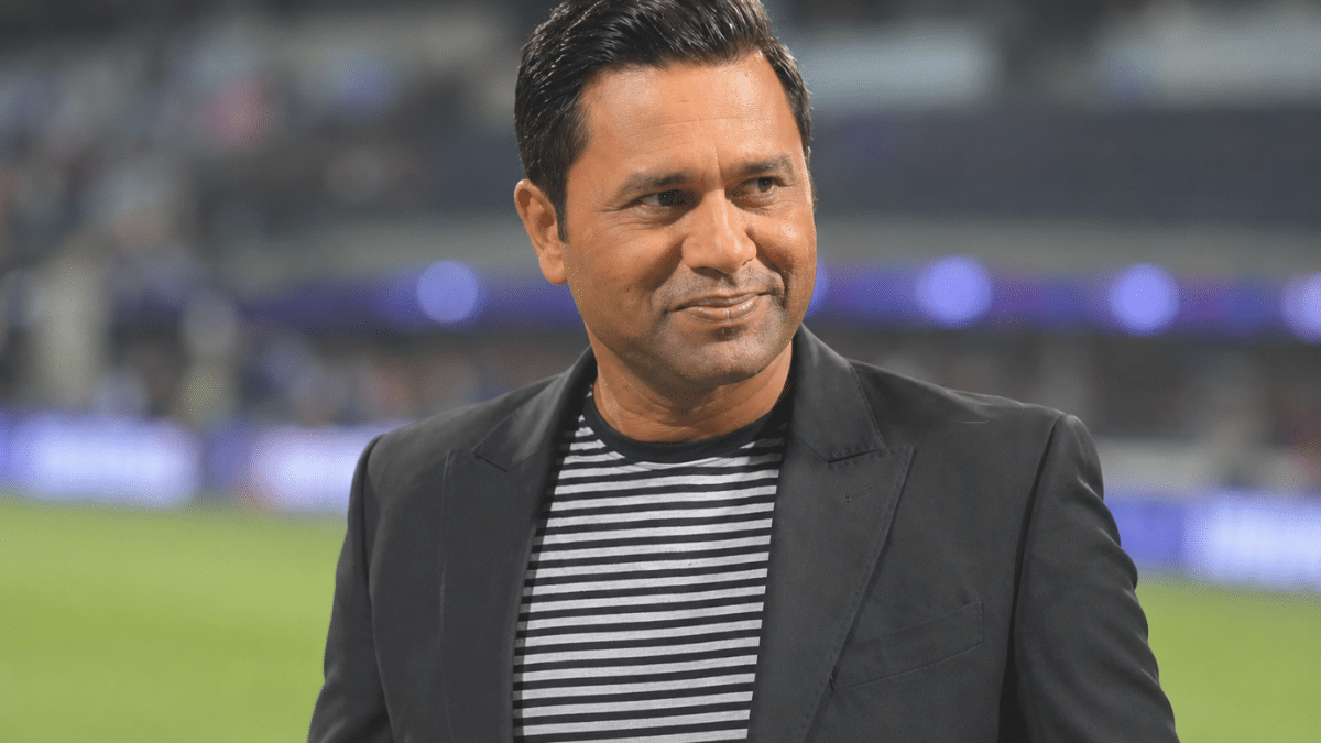 Ultra-realistic close-up portrait of Aakash Chopra in a stadium, captured from a side angle with a blurred background.