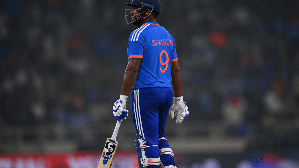 Ultra-realistic rear side-angle photograph of Sanju Samson carrying his bat after a batting, with a blurred stadium background