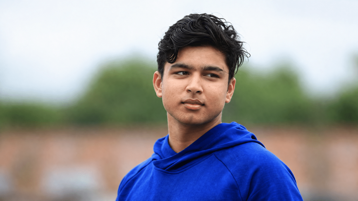 Indian cricket prospect Vaibhav Sooryavanshi looking to the side in a blue hoodie during an outdoor photoshoot.