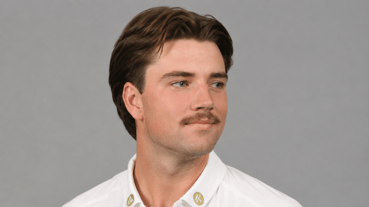 English cricketer James Coles during an official portrait session, looking to the side in a white cricket shirt.