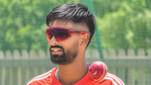Manav Suthar wearing red cricket jersey and red sports sunglasses, posing on a cricket ground.