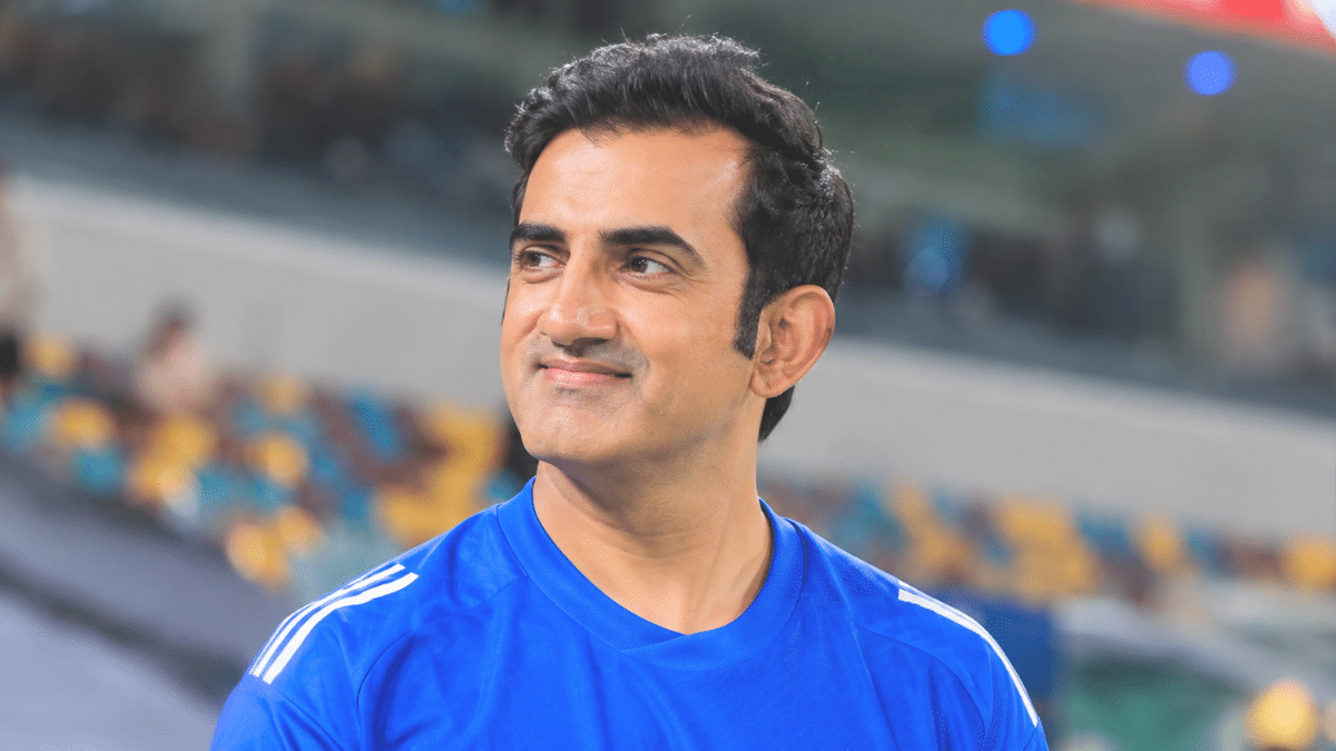 Gautam Gambhir looking to the side while wearing a blue cricket jersey in a stadium.