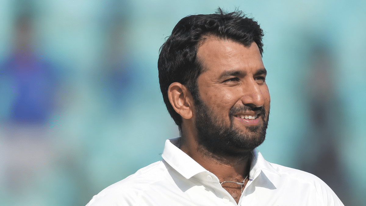 “Cheteshwar Pujara smiling in a white cricket shirt, shown in a right-facing profile against a blurred stadium background.”