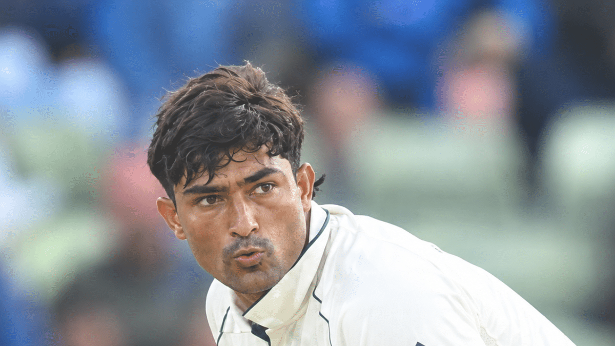 Razaullah in action during a cricket match, wearing a white Test jersey and focused on the play.