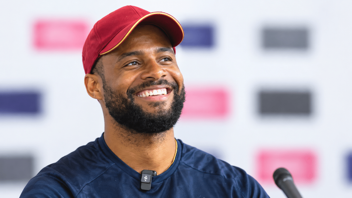 Shai Hope, West Indies wicketkeeper-batter and captain, smiling while wearing a maroon cap and dark training jersey.