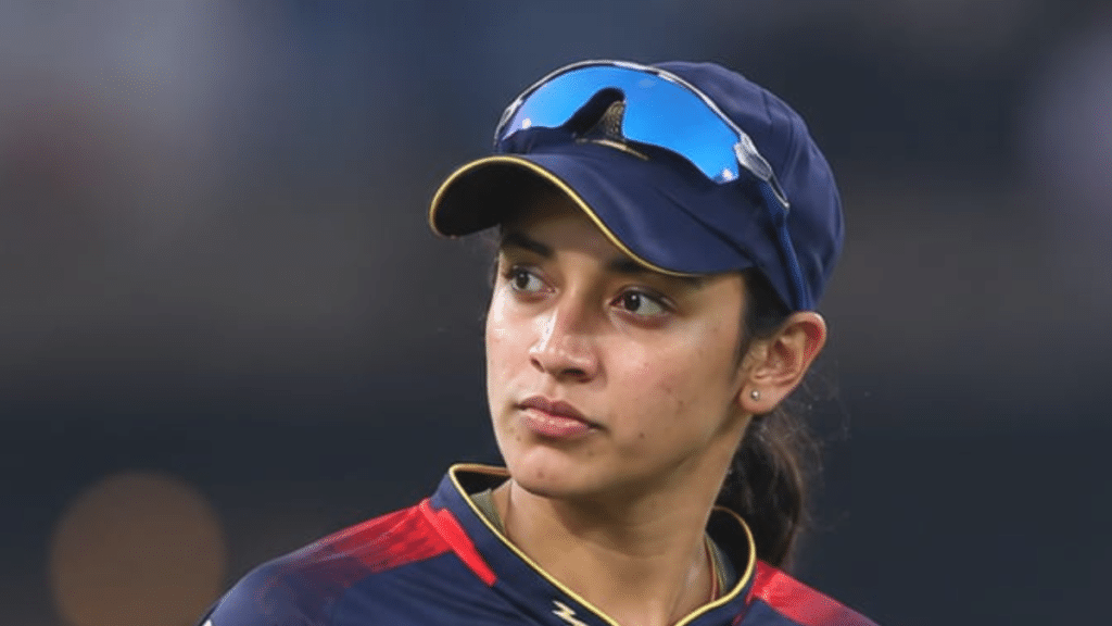 smriti mandhana in a RCB jersey with wearing blue sunglasses on her cap