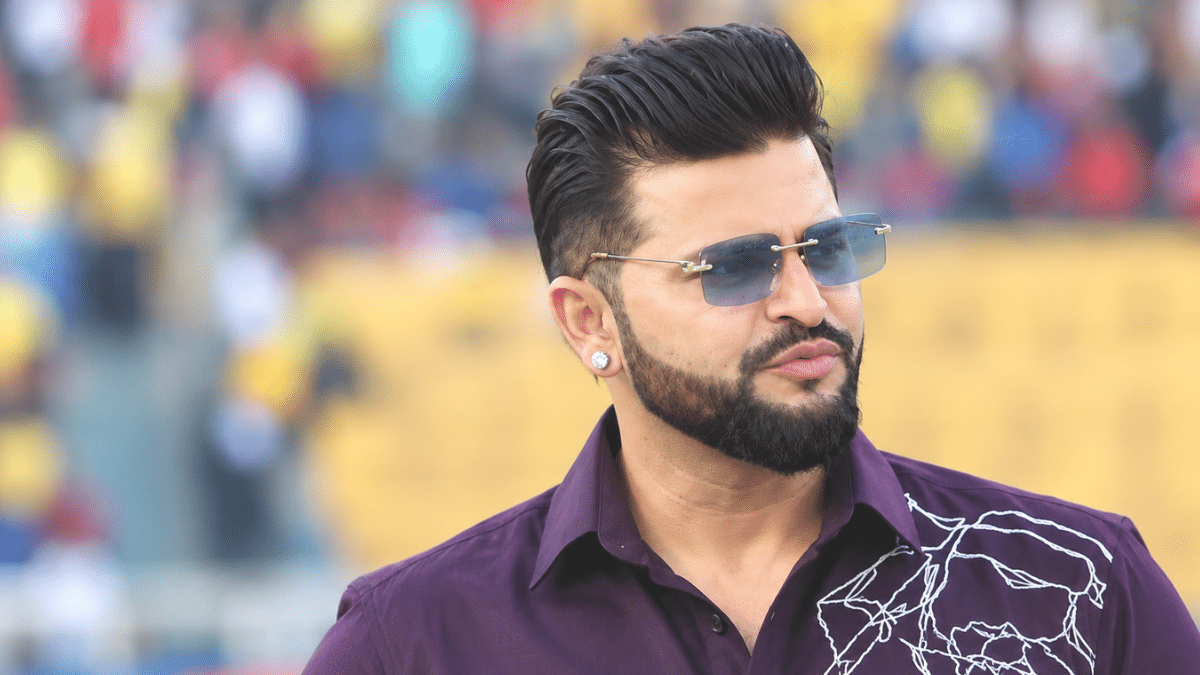 Suresh Raina wearing a stylish dark purple shirt and blue-tinted sunglasses, shown in a right-facing three-quarter profile with a softly blurred stadium background.
