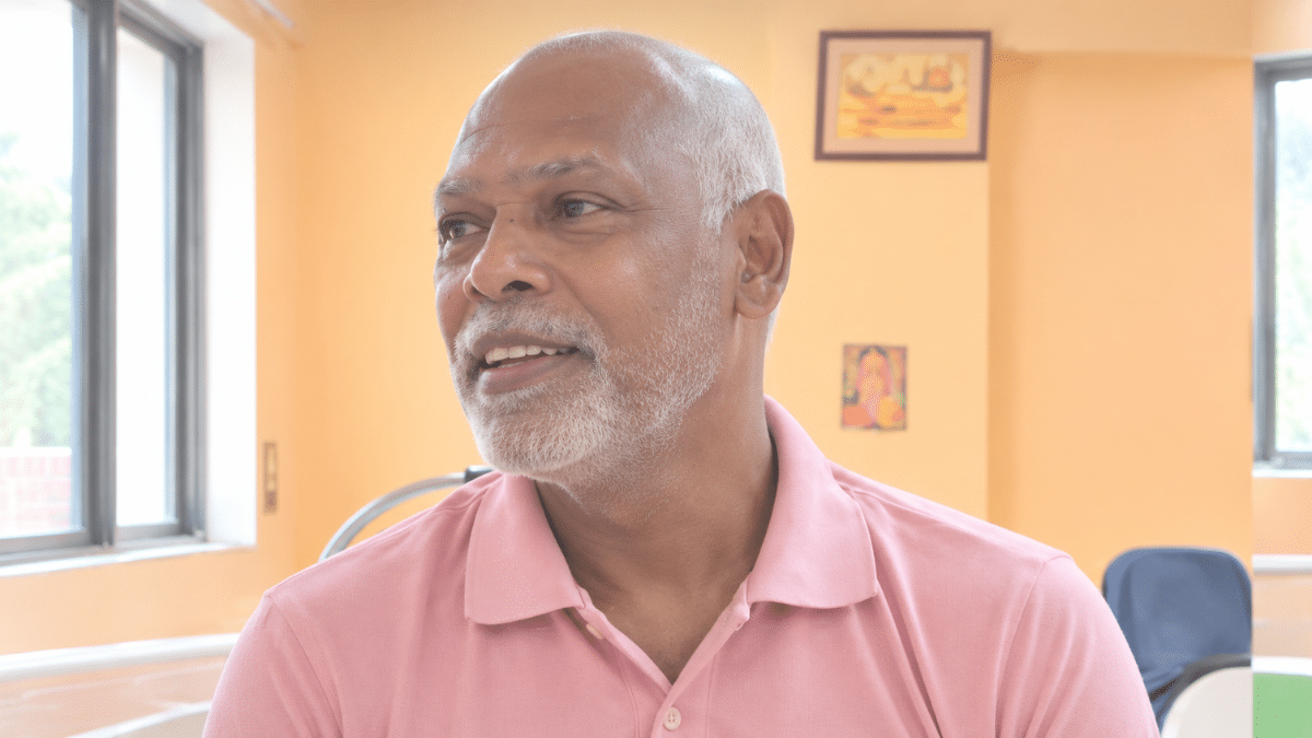 Vinod Kambli seated indoors, wearing a pink polo shirt and looking to the left in a three-quarter profile.