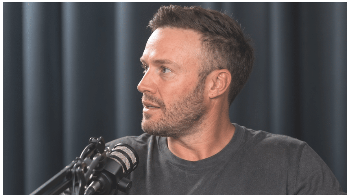 AB de Villiers, former South African international cricketer known as “Mr. 360,” wearing a charcoal T-shirt and speaking into a podcast microphone against a dark studio background.