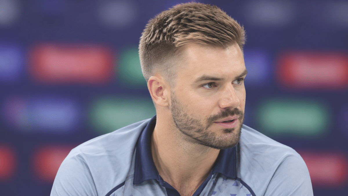 Aiden Markram, South African cricketer, wearing a light blue cricket jersey at a press conference.