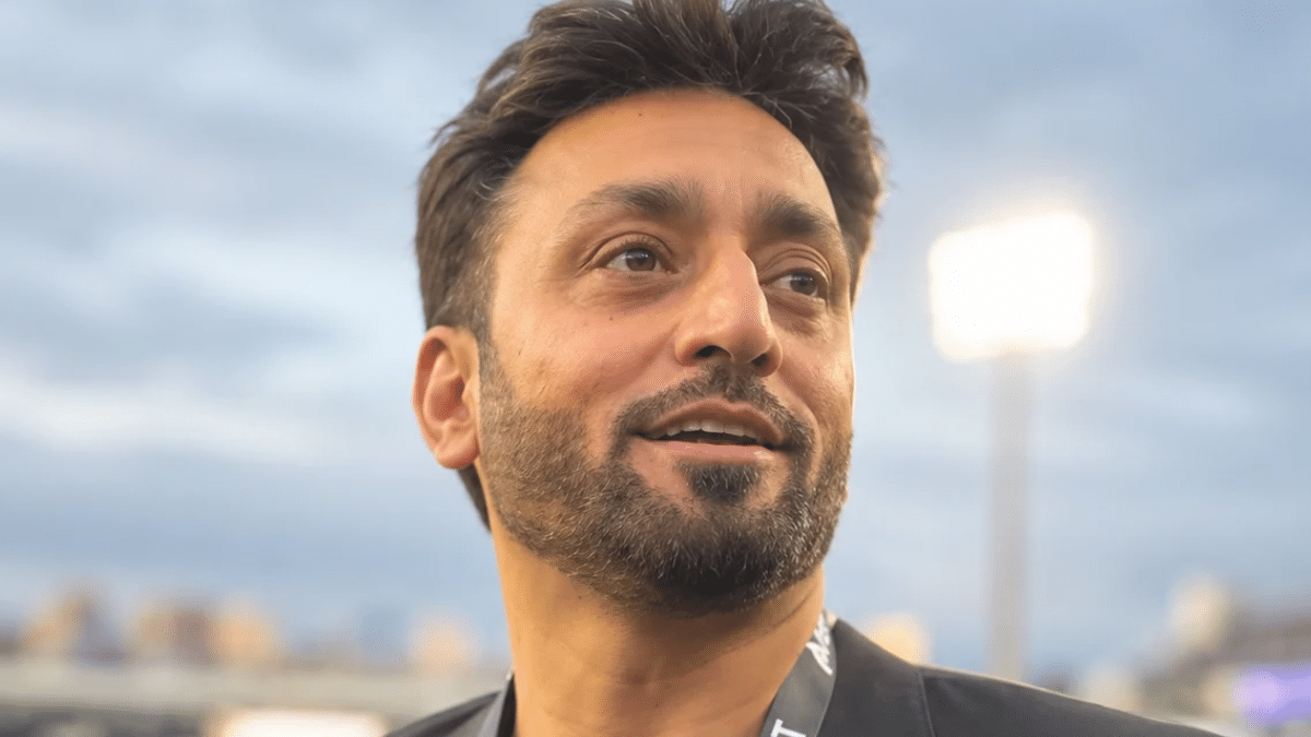 Kamil Khan wearing a black blazer and maroon shirt with a team management lanyard