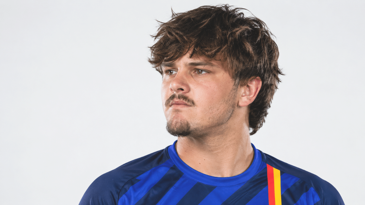 Lwandre Pretorius looking to the left, with wavy brown hair, mustache and goatee, wearing a blue striped sports jersey against a plain white background.