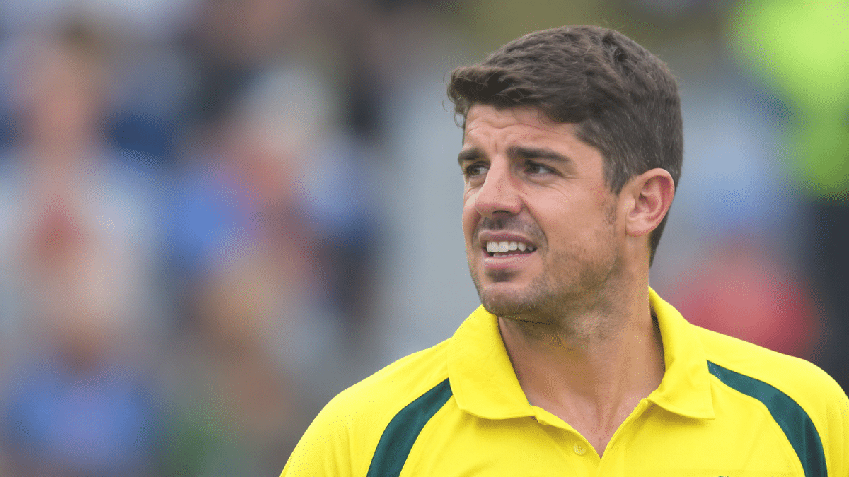 Moises Henriques, Australian cricketer, wearing a yellow cricket jersey with green accents.